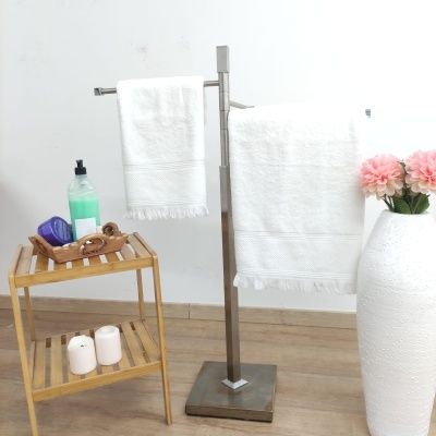 Toalheiro metálico com toalhas brancas e mesa de madeira com sabonetes e velas.