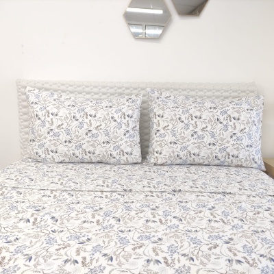 Roupa de cama floral em cama com cabeceira cinza e espelho hexagonal na parede