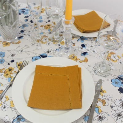 Mesa posta com toalha de flores coloridas e guardanapos mostarda