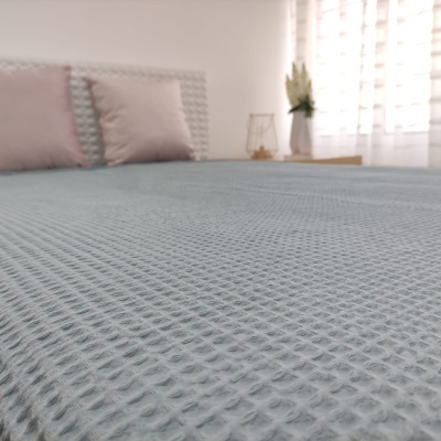 Cama com colcha cinzenta texturizada e almofadas rosa