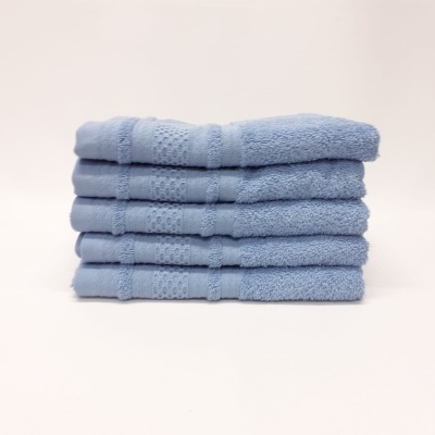 Seis toalhas azuis empilhadas com padrão bordado em fundo branco