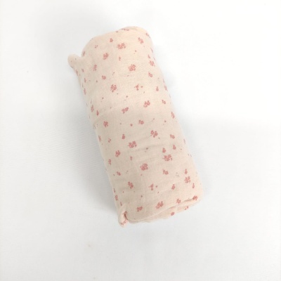 Manta dobrada com padrão de flores cor-de-rosa sobre fundo creme