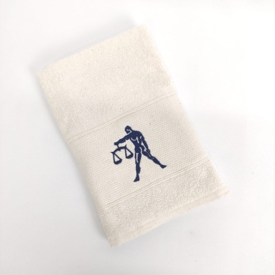 Toalha de rosto branca com bordado azul de figura humana e balança