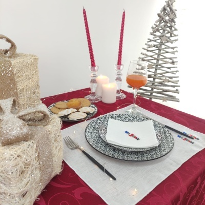 Mesa posta com prato decorativo, guardanapo, velas e copo com bebida