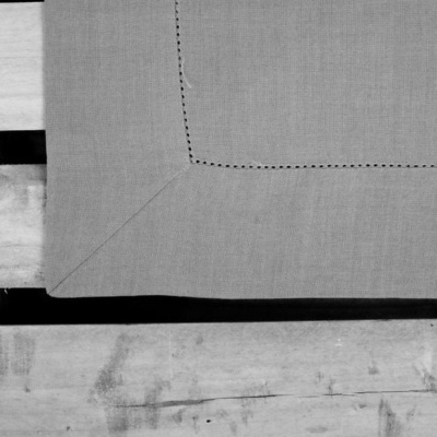 Toalha cinza com costura preta sobre superfície de madeira clara