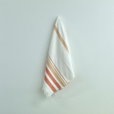 Toalha branca com riscas terracota e bege pendurada na parede