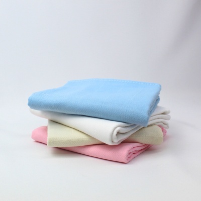 Três mantas dobradas coloridas empilhadas numa superfície branca