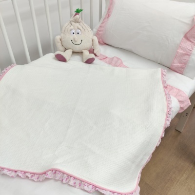Cama de bebé com roupa de cama branca e rosa e almofada em forma de dente sorridente