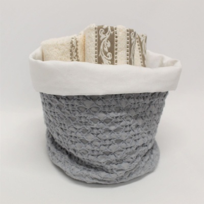 Cesto cinzento com aba branca e toalhas bege com padrões