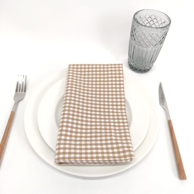 Conjunto de jantar com pratos brancos, guardanapo xadrez, talheres de cabo madeira e copo de vidro