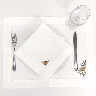 Toalha de mesa branca com guarda-napo branco, prato, talheres e copo