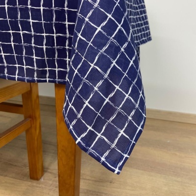 Toalha de mesa azul com padrão de grelha branca pendurada numa mesa de madeira clara