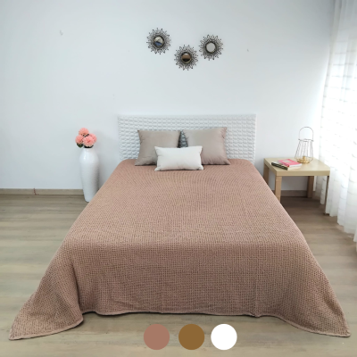 Quarto com cama solteiro, manta castanha, três almofadas, cabeceira branca, vaso com flores, mesa amarela e espelhos decorativos