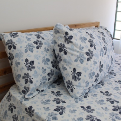 Cama com roupa de cama com padrão de folhas azuis e pretas