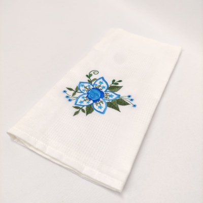 Toalha branca com bordado de flor azul