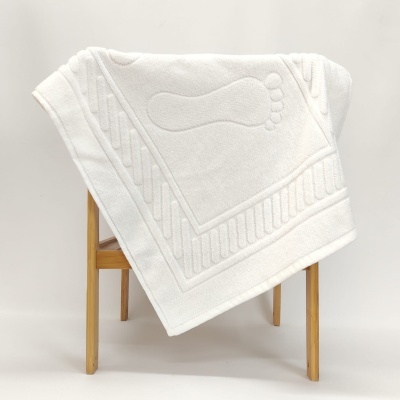 Toalha branca com desenho de pegada em relevo sobre banco de madeira