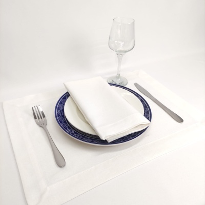 mesa posta com prato azul, talheres e copo sobre pano branco