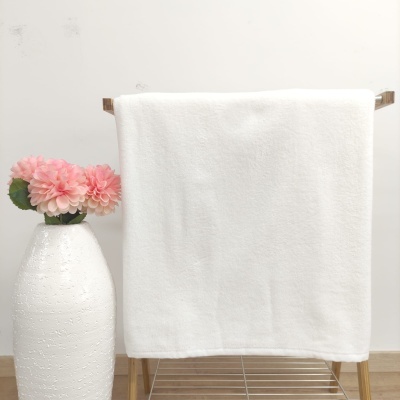 Toalha branca pendurada em suporte de madeira ao lado de vaso branco com flores cor-de-rosa