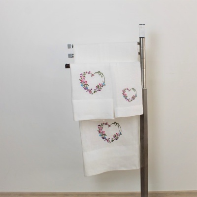 Conjunto de toalhas brancas com bordado de corações florais penduradas em suporte metálico