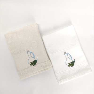 Duas toalhas de mão bege e branca com bordado de garrafa azul e folhas verdes.