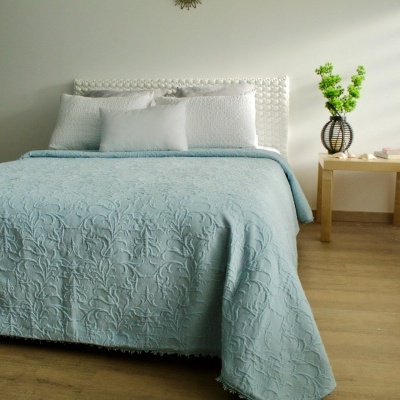 Quarto com cama azul e almofadas brancas ao lado de mesa de cabeceira com vaso de flores