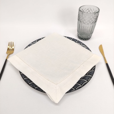 Utensílios de mesa com prato preto e branco, guardanapo branco, talheres pretos e dourados e copo transparente
