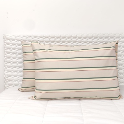 Duas almofadas com riscas verdes e vermelhas em tecido bege sobre cama branca