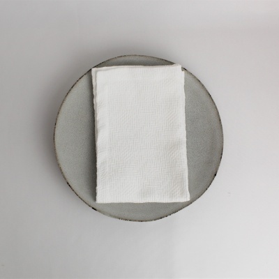 Guardanapo branco dobrado sobre prato cinzento redondo