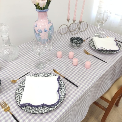 Mesa com toalha xadrez, pratos com padrão floral, velas e jarro decorativo
