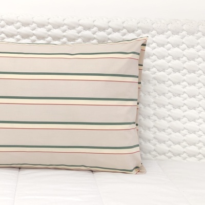 Fronha às riscas horizontais verdes e vermelhas sobre fundo bege em cama branca com cabeceira estofada branca.
