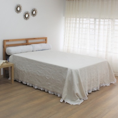 Cama de madeira com colcha branca e travesseiro cilíndrico em quarto com cortina branca e espelhos decorativos na parede
