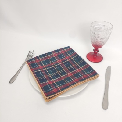 Conjunto de talheres, prato branco com guardanapo xadrez e copo com pé vermelho