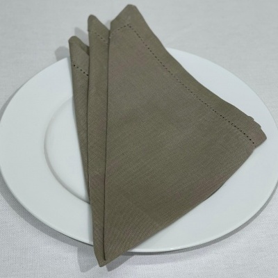 Guardanapo de tecido castanho dobrado sobre prato branco