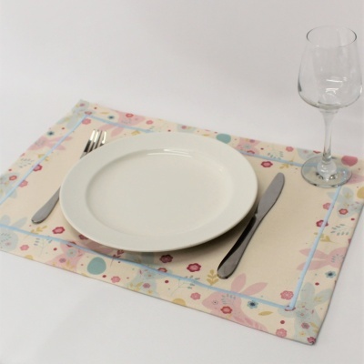 Mesa posta com prato branco, talheres de metal, copo de vidro e toalhete floral