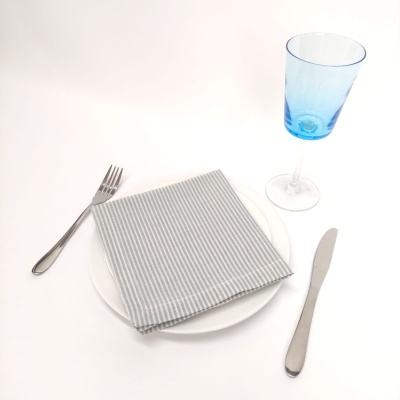 Conjunto de mesa com prato branco, guardanapo riscado, talheres prateados e copo azul