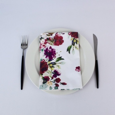 Prato branco com guardanapo floral e talheres com cabo preto