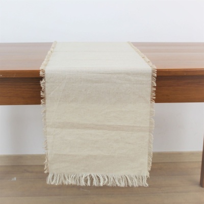 Caminho de mesa em tecido cru com franjas sobre mesa de madeira