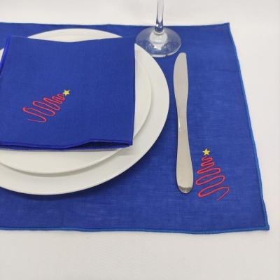toalhete e guardanapo azuis com bordado vermelho e amarelo, prato branco, faca e copo