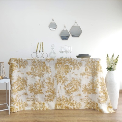 Mesa com toalha branca e dourada, copos, pratos, castiçais e espelhos hexagonais na parede branca