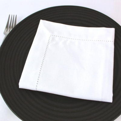 Guardanapo branco sobre prato preto com garfo ao lado