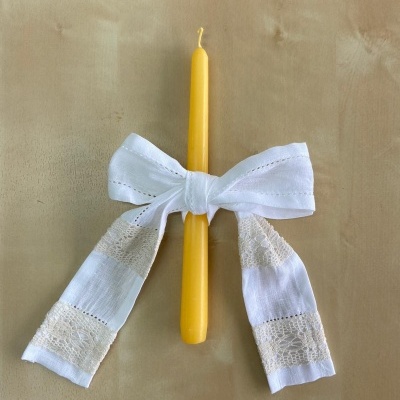 Vela amarela com laço branco de tecido rendado