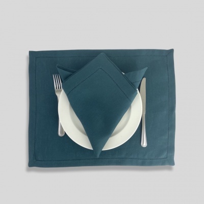Jogo americano e guardanapo azuis com prato branco e talheres ao centro