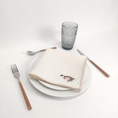 Conjunto de mesa com talheres de cabo em madeira, prato branco, guardanapo bordado e copo cinzento