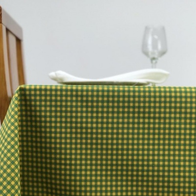 Toalha quadriculada verde e amarelo sobre mesa com guardanapo e copo
