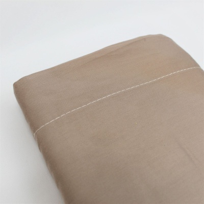 Lençol castanho claro dobrado com costura branca