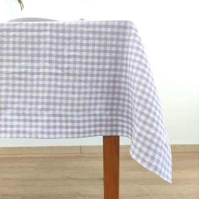 Toalha de mesa xadrez lilás e branco sobre mesa de madeira