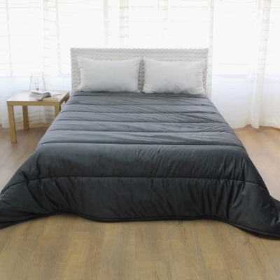 Cama de casal com colcha cinza escura e almofadas brancas