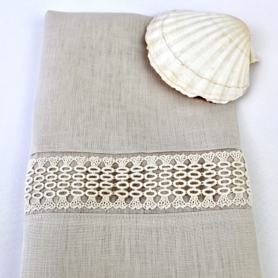 Toalha bege claro com renda branca e concha branca em fundo branco