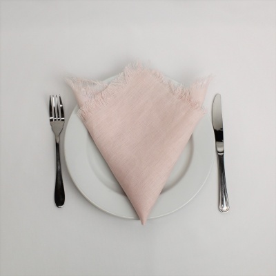 Guardanapo rosa claro em prato branco com talheres ao lado