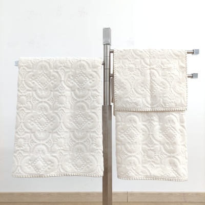 Toalhas brancas bordadas penduradas num suporte de metal prateado